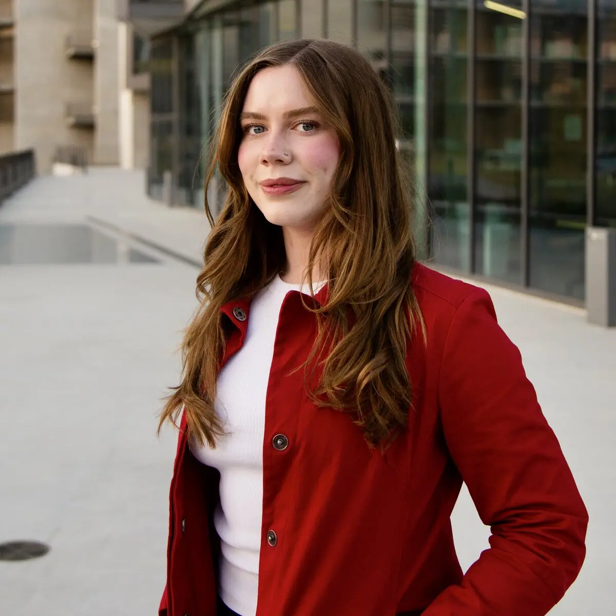Olivia Gale in a red jacket outside a glass-fronted campus building