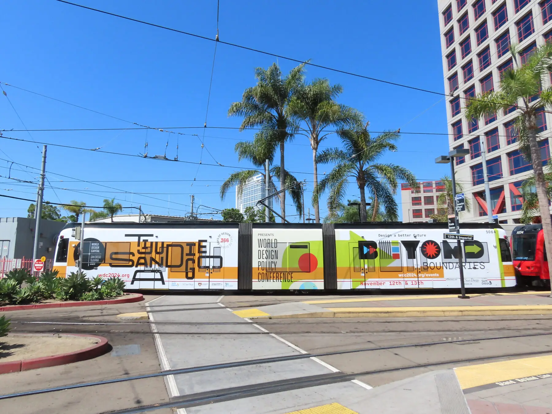 A trolley wrapped in conference graphics on a downtown street