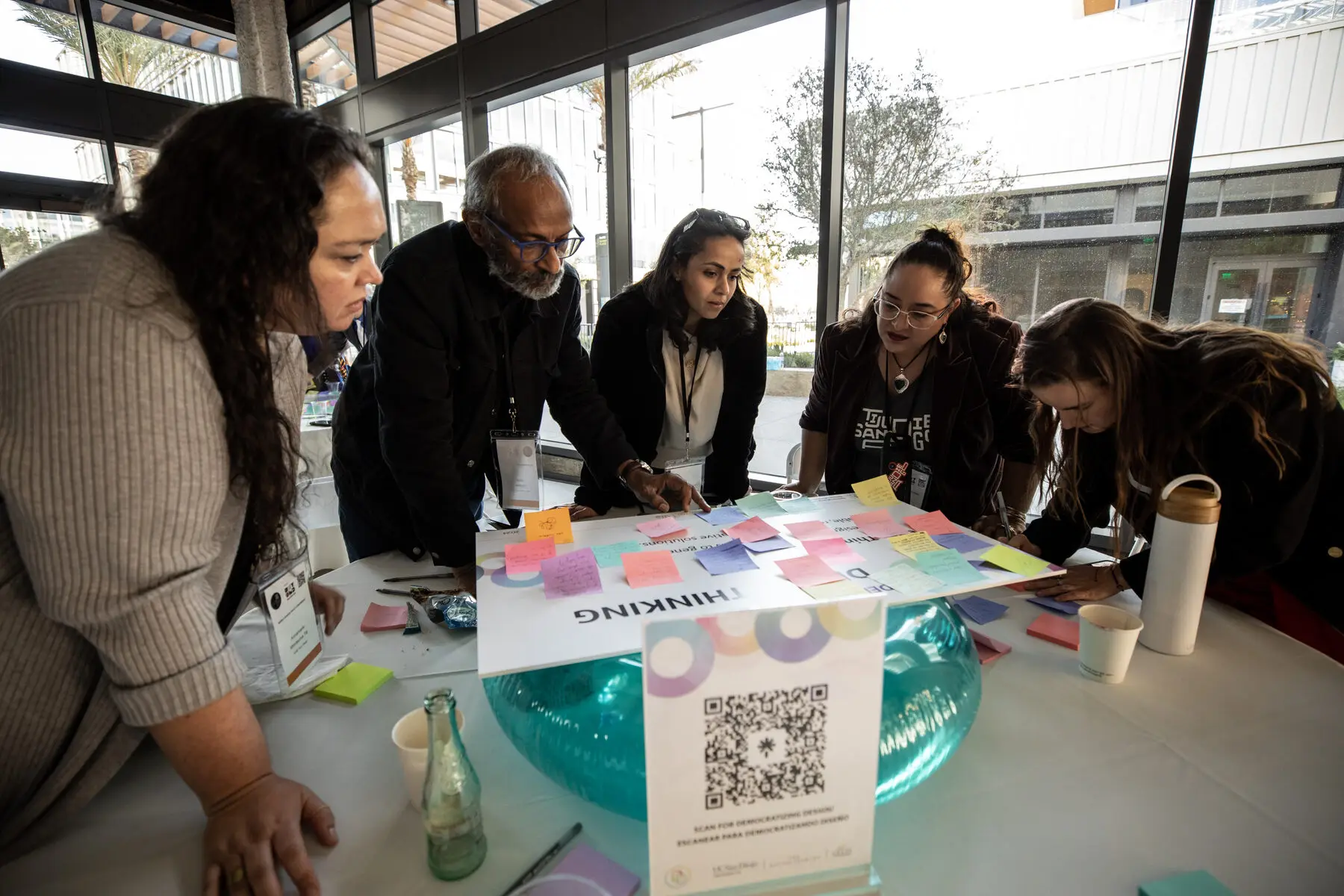 Participants lean over a table covered in sticky notes