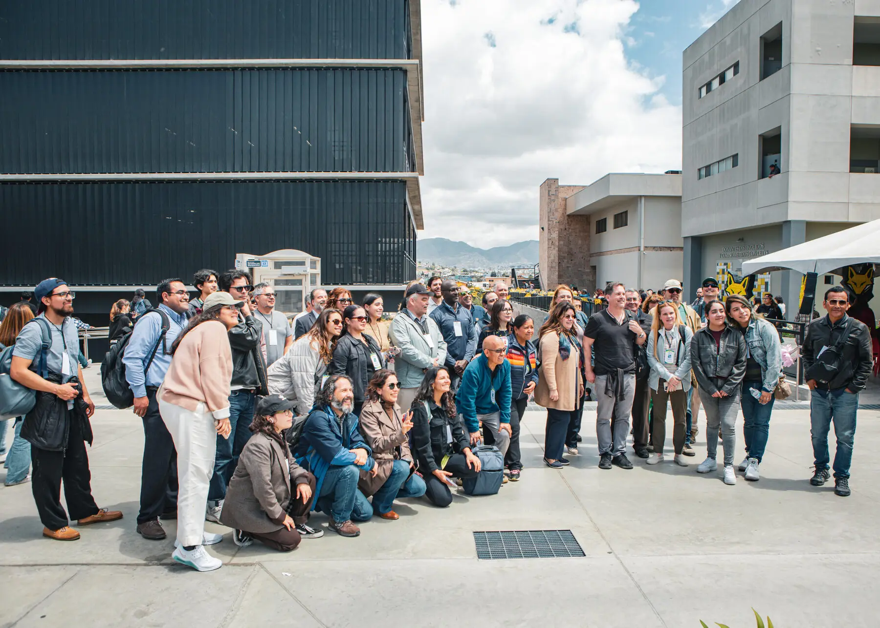 A large group of network members poses together on a plaza