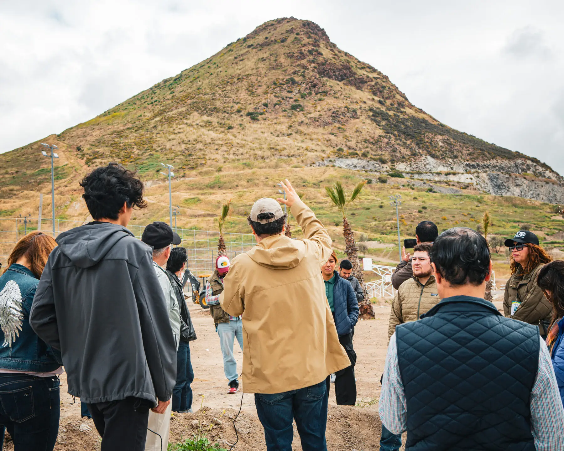 A Design to Action Network group gathered at the foot of a steep hill, listening to a guide